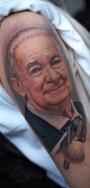 Smiling elderly man with a shaving brush, colour portrait on an upper arm.