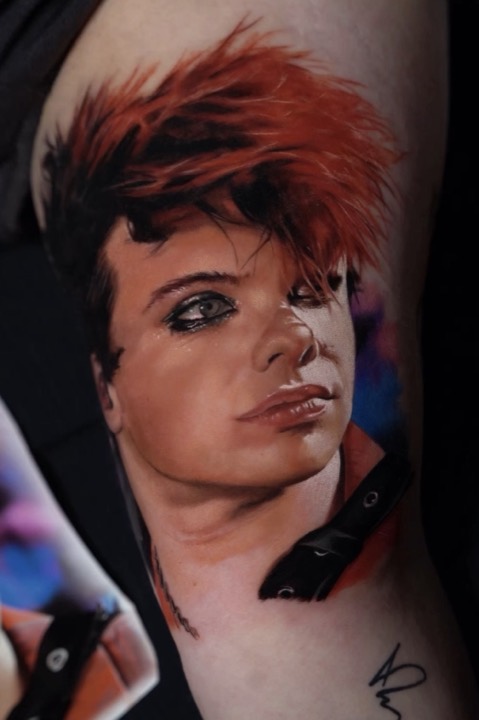 Young man with spiked red hair and smudged eyeliner, colour portrait on an inner arm.